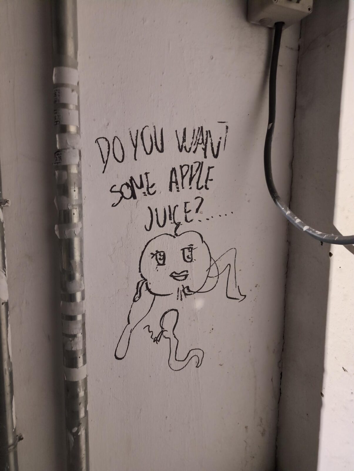 An apple character drawn on a wall beneath the words Do you want some apple juice?