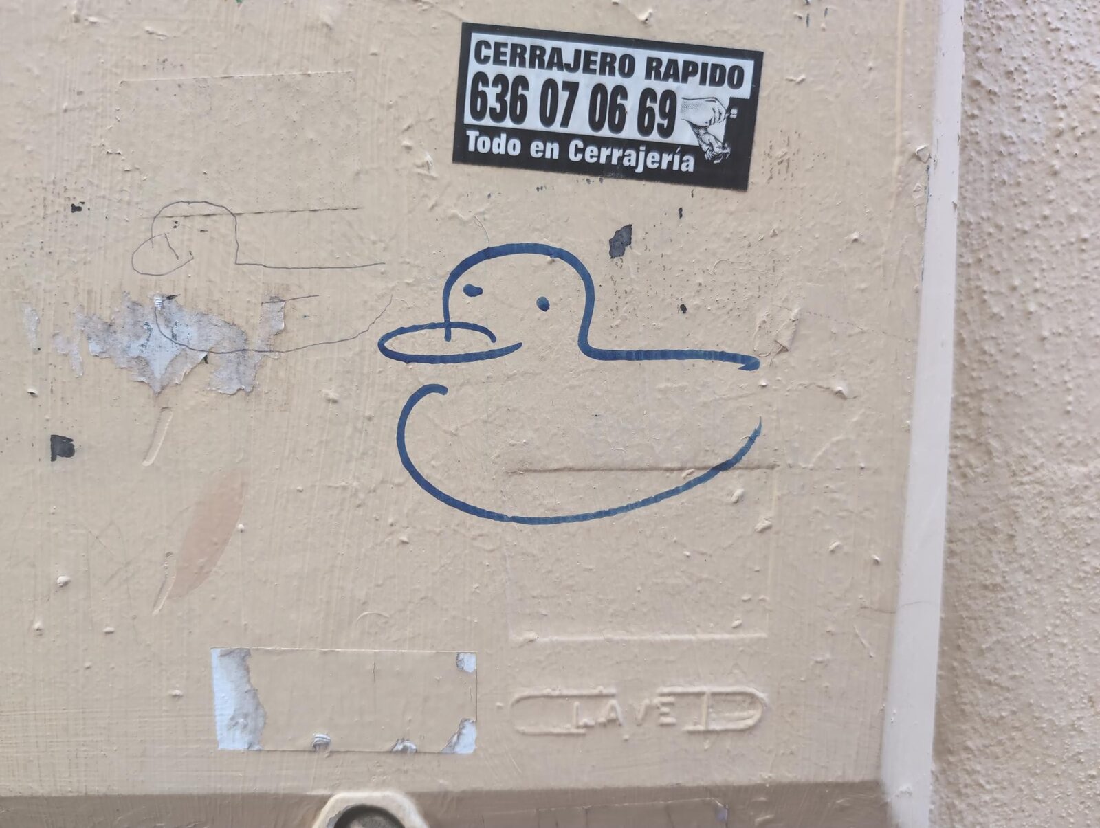 A blue outline of a duck drawn beneath a locksmith sticker
