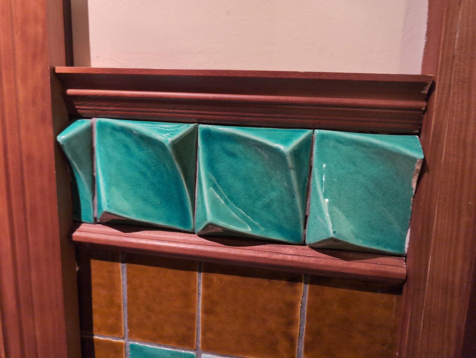 Raised green ceramic tiles set into a wooden frame above orange tiles