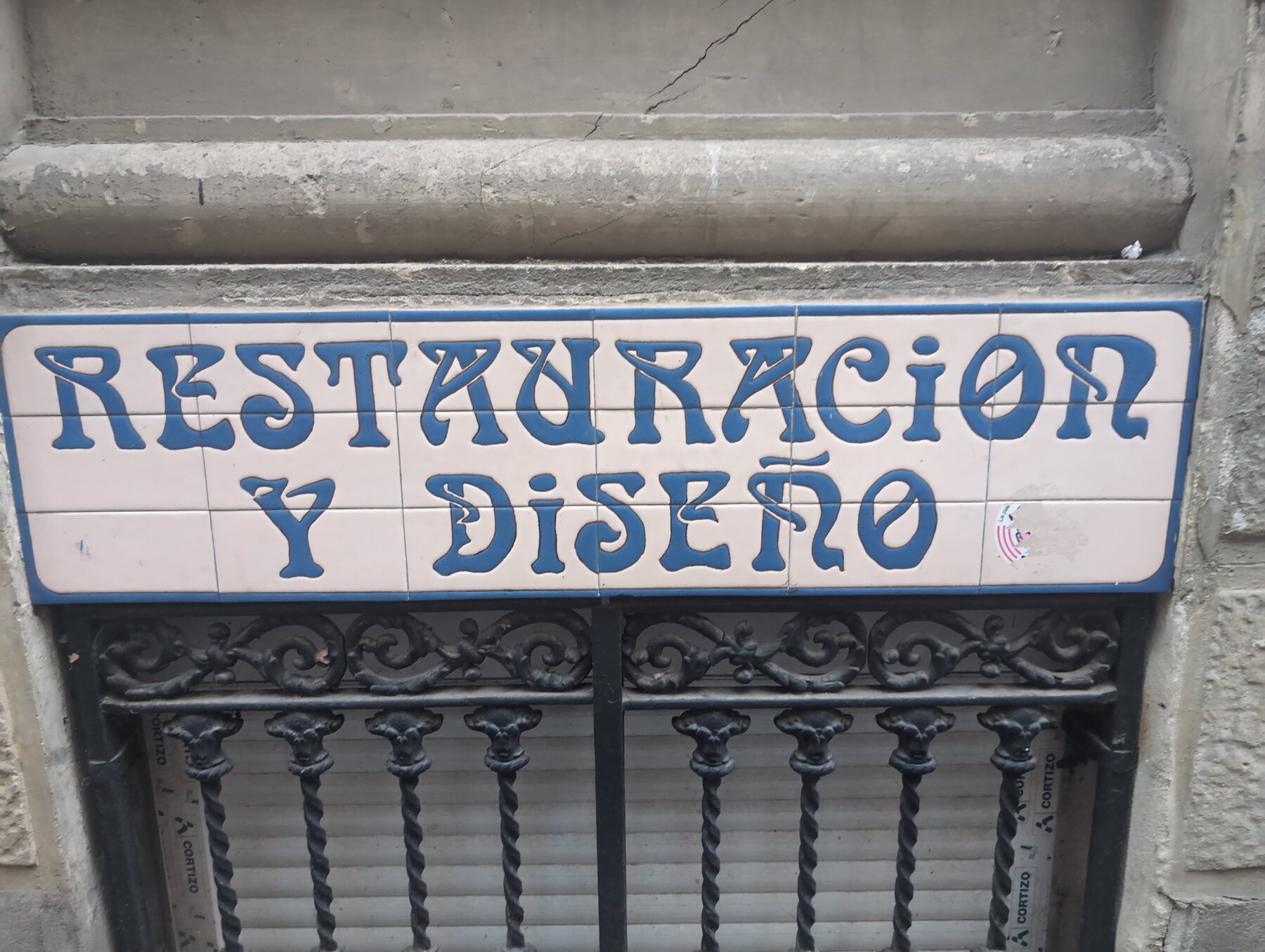A tiled Restauración y Diseño sign on a building in Madrid