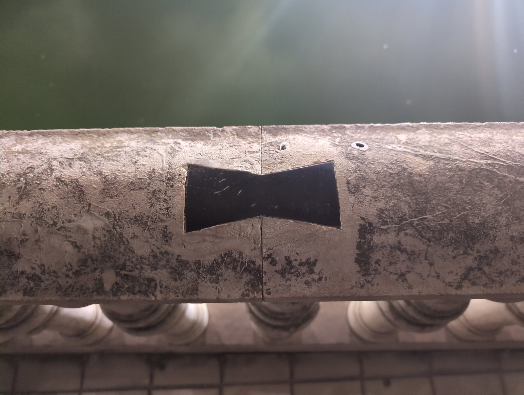 A bow-tie-shaped joint cut into the stone railing at Plaza de España